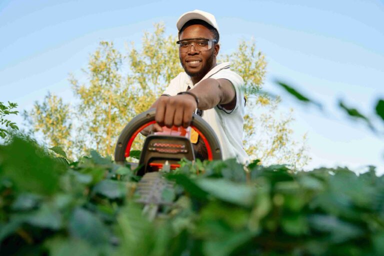 portrait-cheerful-african-man-pruning-hedge-with-trimmer_11zon